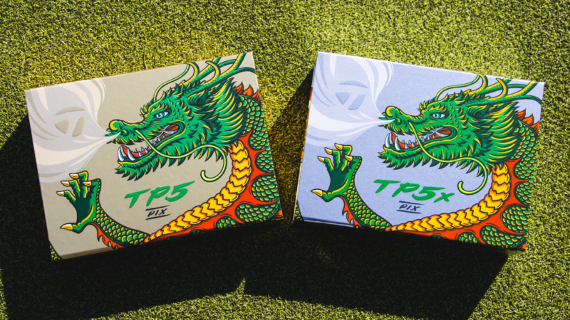 the left is the TP5 Box for the Taylormade Dragon Golf Balls, and on the right is the box for the TaylorMade TP5x Dragon golf balls laying on grass.