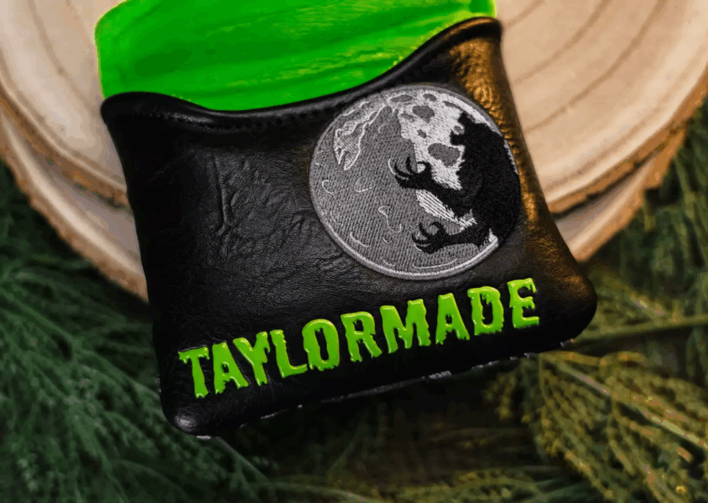 A close up of the Midnight Howl Spider Tour X putter's head cover. TaylorMade is spelled in green goo lettering while a werewolf howls at the moon.