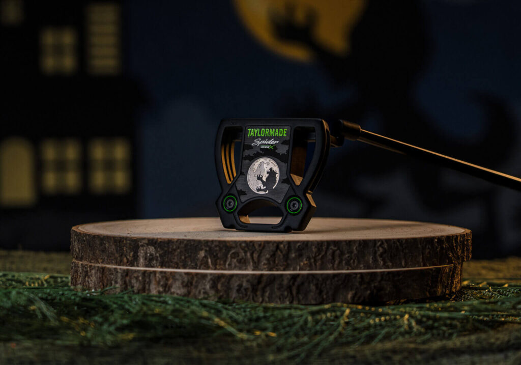 The head of Midnight Howl Spider Tour X putter. It features a werewolf silhouetted against a full moon. The TaylorMade logo looks like it is written in green goo.