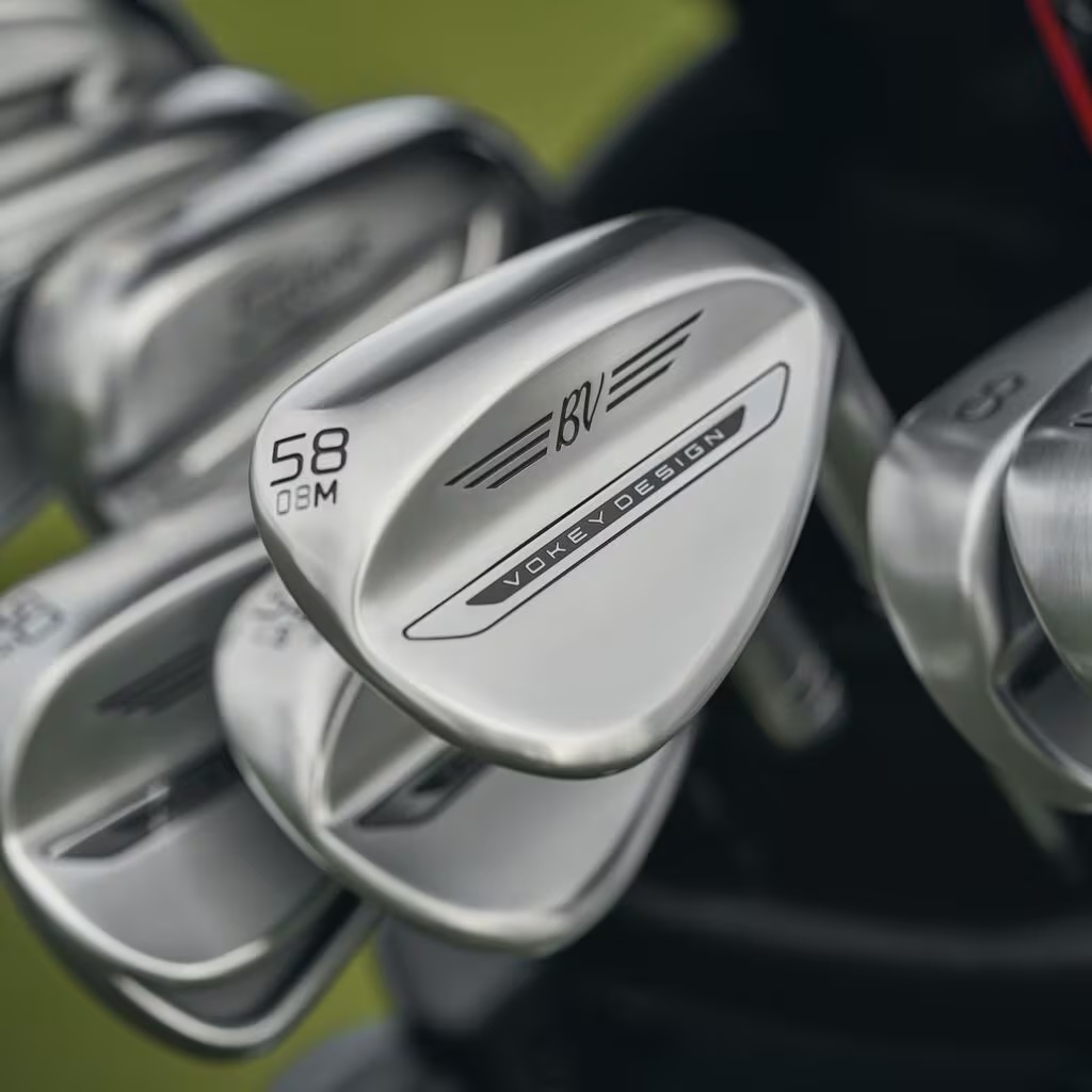 A close up of a bag with several Titleist irons and a Vokey SM11 wedge in focus.